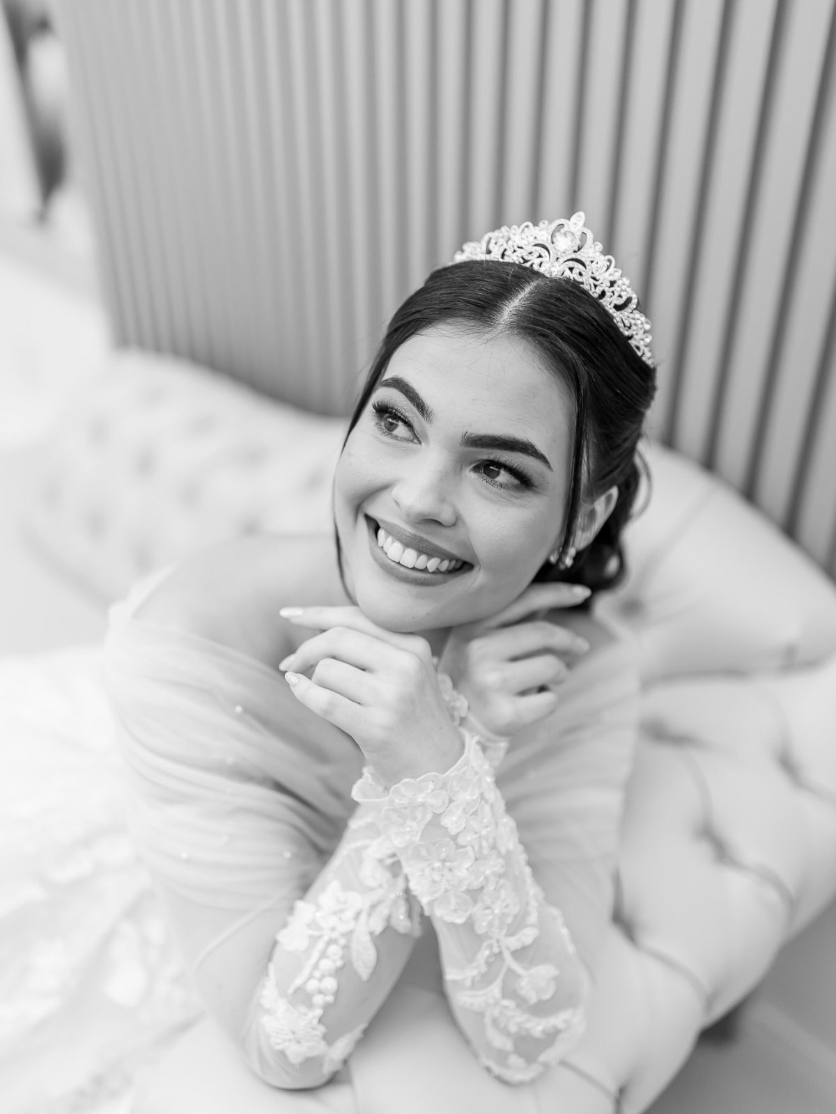 Retrato em preto e branco de uma noiva sorrindo, com tiara e vestido de renda.