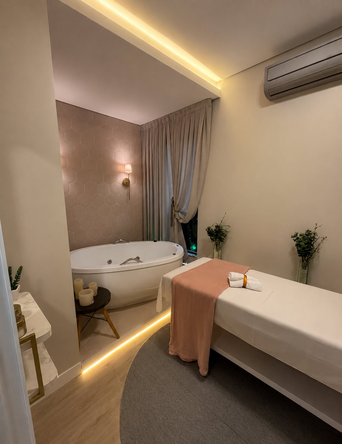 Sala de spa com maca de massagem, banheira e iluminação quente.